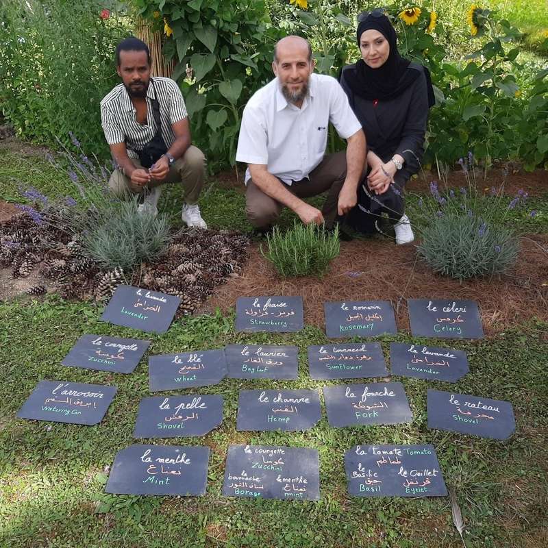 Les 3 collaborateurs bénévoles avec des paneaux en 3 langues